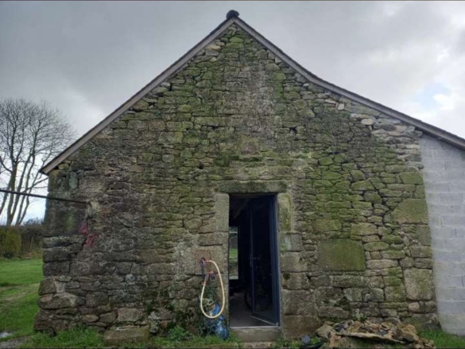 Avant — Restauration de longère bretonne en pierre, façade couverte de mousse et lichen (Ploerdut)