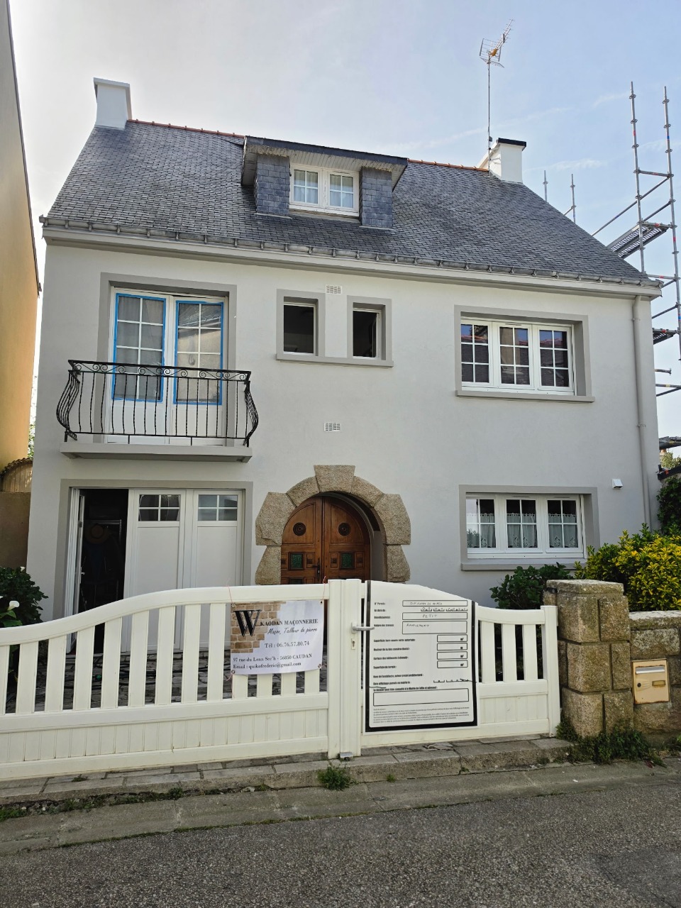 Maison entièrement ravalée par Kaodan Maçonnerie à Port-Louis, avec encadrement de porte en pierre taillée et panneau de chantier visible