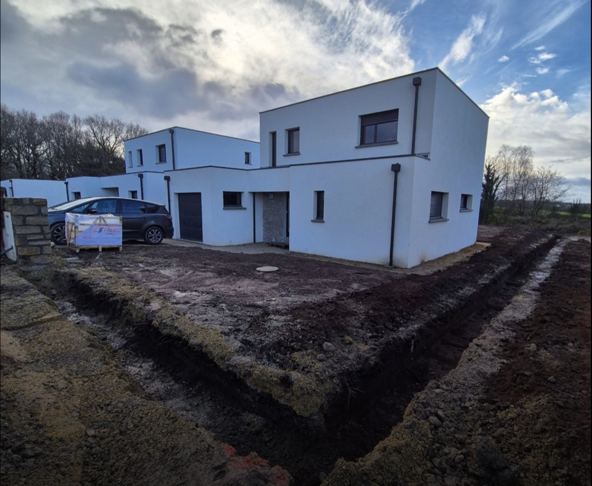Avant — chantier de terrassement avec tranchées ouvertes pour fondations devant la maison contemporaine